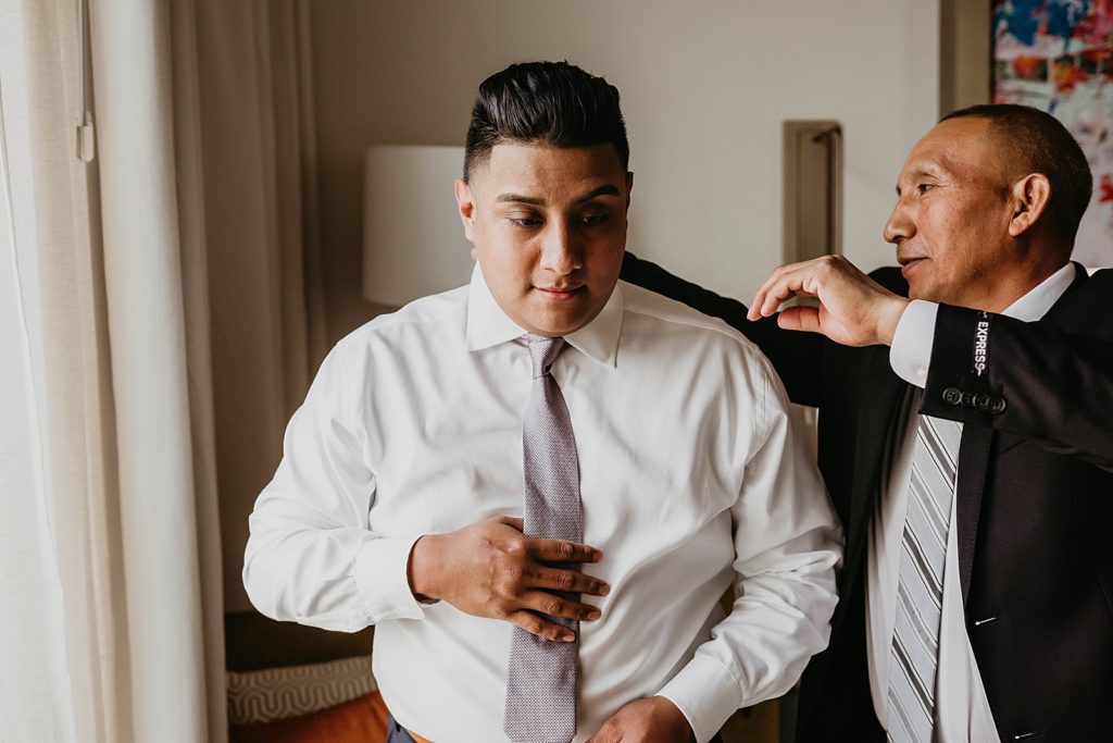 Groom getting ready putting on tie
