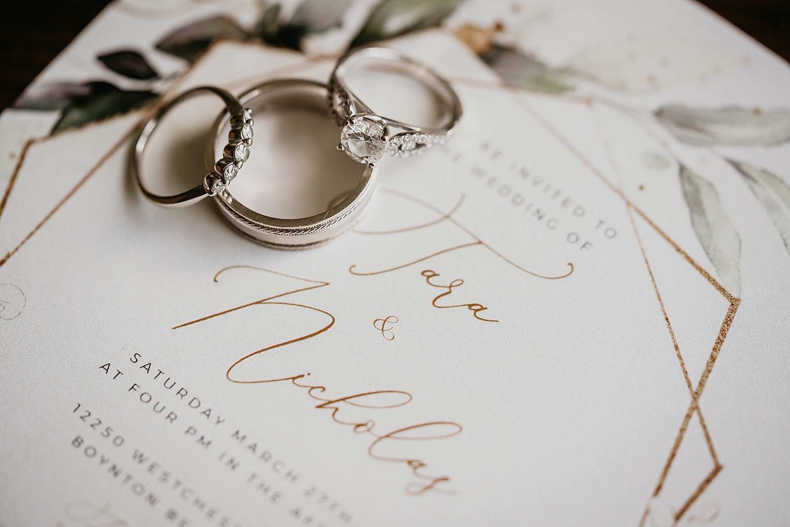 Detail shot of invitation engagement ring and wedding bands